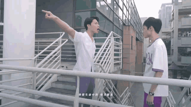 a man in a purple shirt with the letter n on it stands next to a man in a white shirt