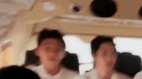 a group of people are sitting on a plane covering their faces .