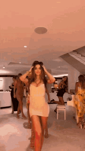 a woman in a white dress is standing in front of a group of women