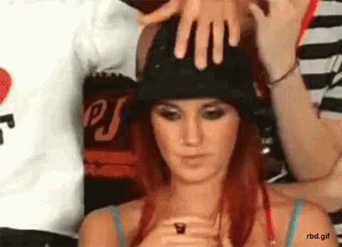 a woman wearing a black hat is being touched by a man .