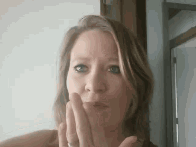 a woman with a ring on her finger is covering her mouth with her hand