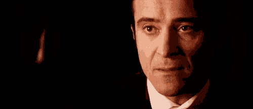 a man in a suit and tie is looking at the camera in a dark room