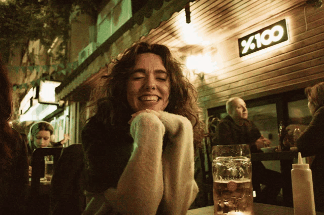 a woman is smiling in front of a sign that says x100