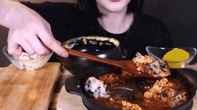 a woman is eating food with a wooden spoon