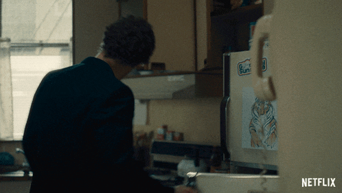 a man standing in a kitchen next to a refrigerator that has a sticker on it that says sunny