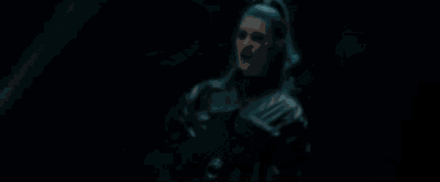 a woman is singing into a microphone on a stage in a dark room .