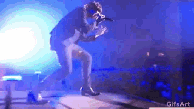 a man in a suit is singing into a microphone on a stage in front of a crowd .