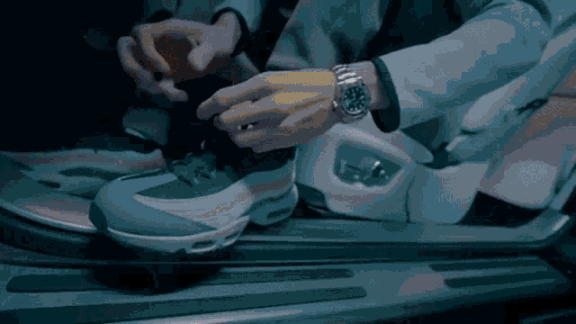 a person wearing a watch is tying their shoe