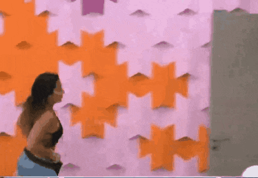 a woman in a black top is standing in front of an orange and pink wall