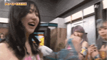 a woman is laughing and holding a bottle of water while another woman looks on .