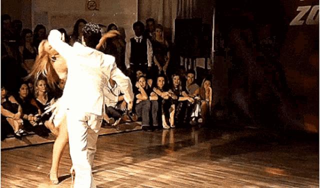 a man and a woman are dancing on a dance floor in front of a crowd with a sign that says no smoking