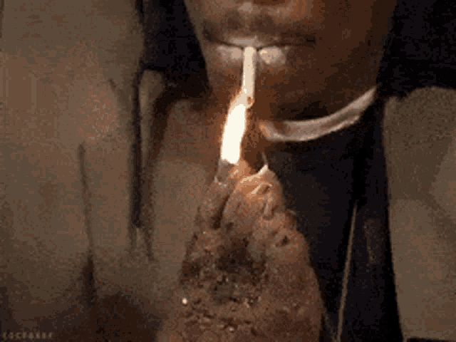a man is lighting a cigarette with a lighter in his mouth .