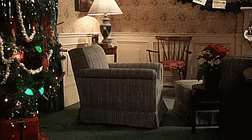 a living room decorated for christmas with a chair a lamp and a christmas tree