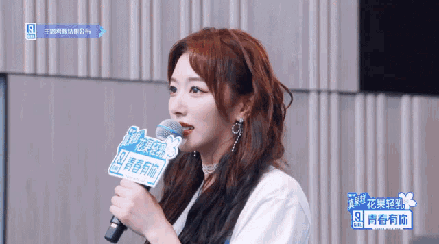 a woman with red hair is holding a microphone with a sticker on it that says ' youth ' on it