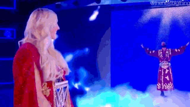 a woman in a red cape is standing next to a man in a red robe on a stage .