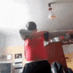 a man in a red shirt is standing in a room .