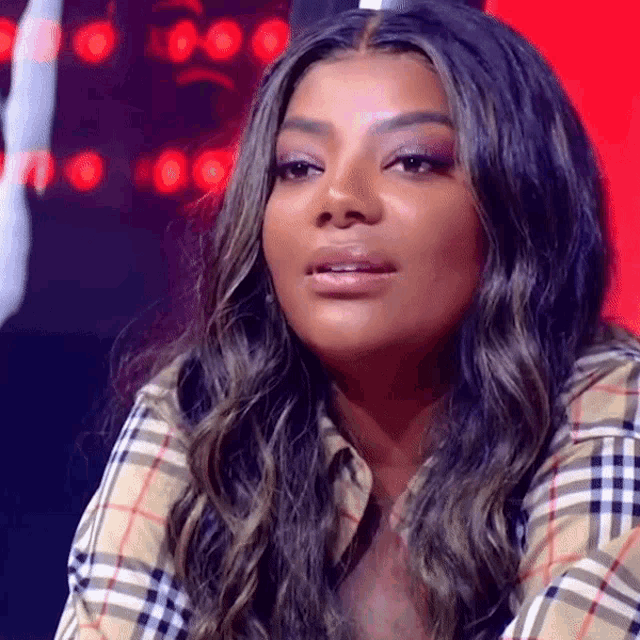 a woman wearing a plaid shirt is looking at the camera