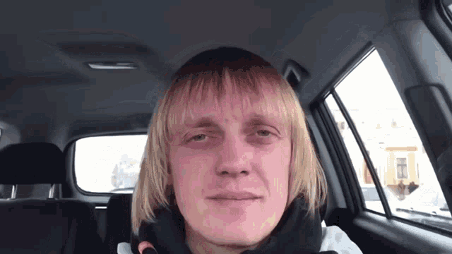a man with blonde hair sitting in a car