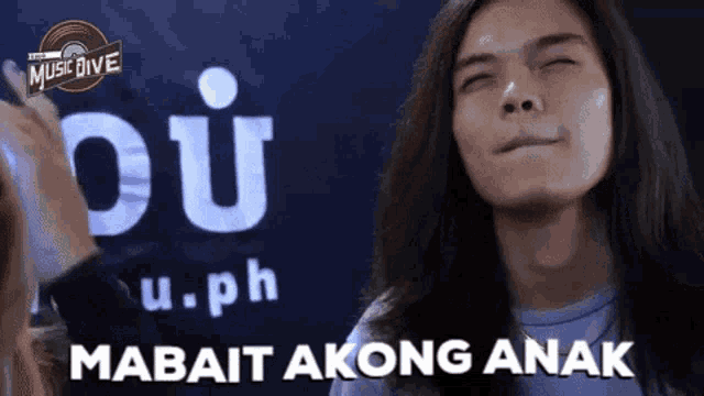 a man with long hair is making a face in front of a music dive sign