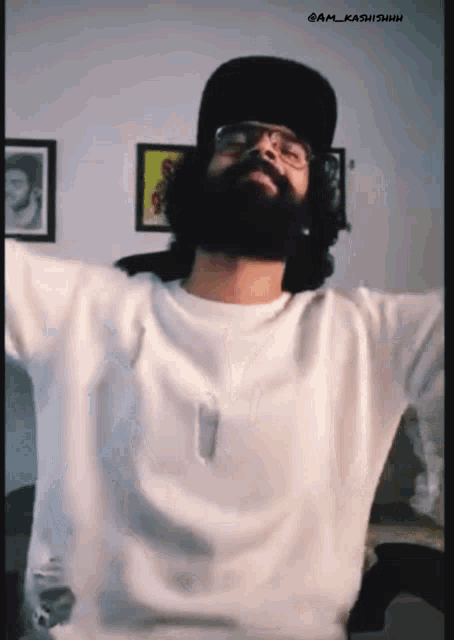 a man with a beard and headphones is wearing a white shirt and black hat