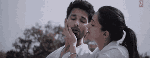 a woman is kissing a man on the cheek while they are standing next to each other .