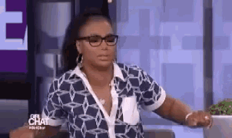 a woman wearing glasses and a blue shirt is sitting in front of a laptop computer .