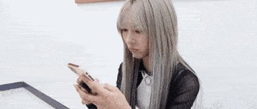 a woman is sitting at a table looking at her cell phone .
