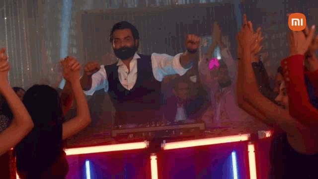a man with a beard is playing music in front of a crowd with a mi logo in the background