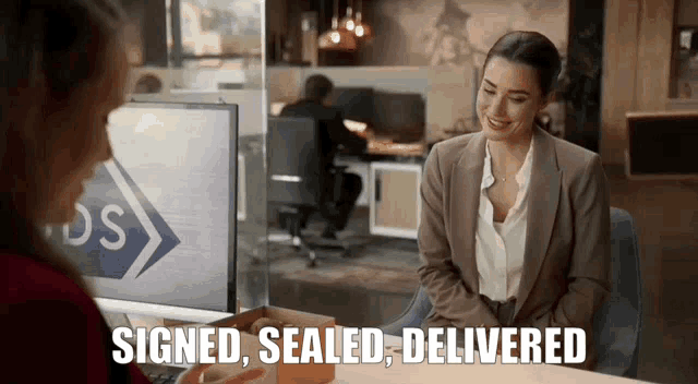a woman is sitting at a desk with a box and the words signed sealed delivered