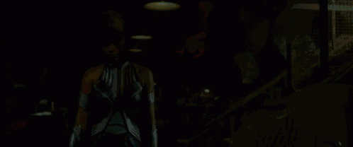 a close up of a woman 's face in a dark room with pink lights .