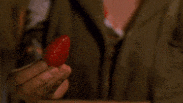 a close up of a person holding a strawberry in their hands .