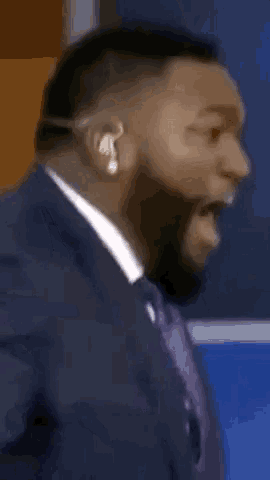 a man in a suit and tie is wearing a headset and making a funny face