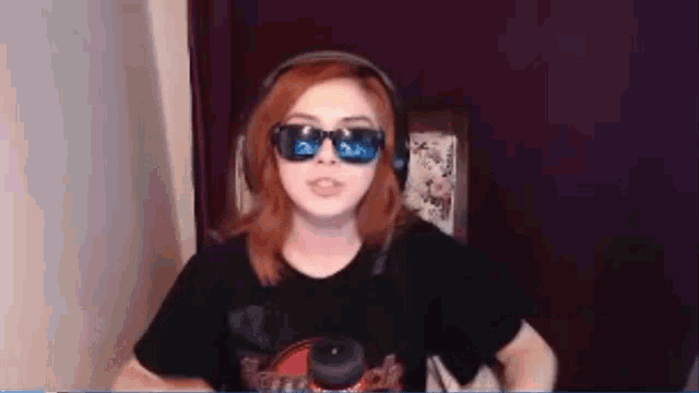 a woman wearing headphones and sunglasses is sitting in front of a computer screen .