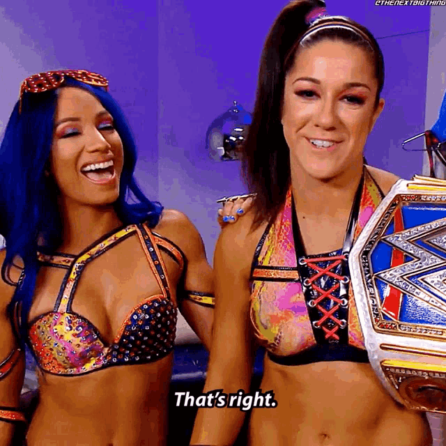 two women are standing next to each other and one of them is holding a championship belt and saying that 's right .