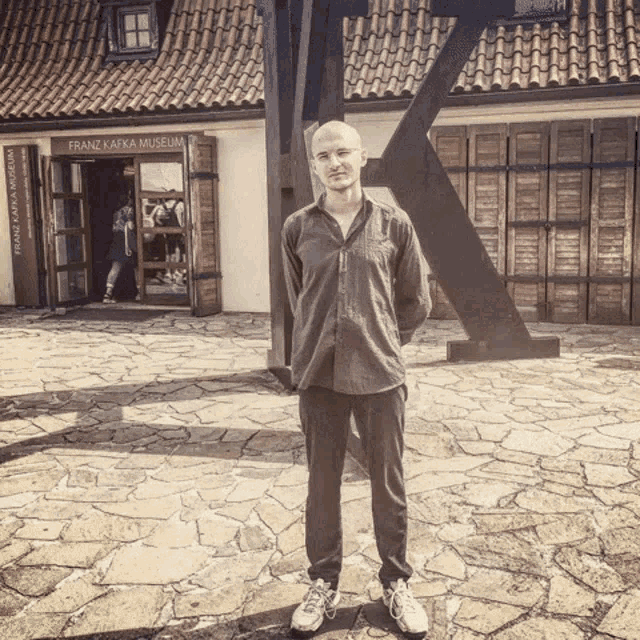 a man standing in front of a building that says franz kafka museum