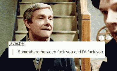 a man in a suit and tie is talking to another man in front of a staircase .
