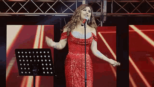 a woman in a red dress stands in front of a microphone