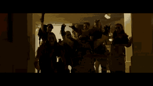 a group of people standing in a dark room with their arms in the air