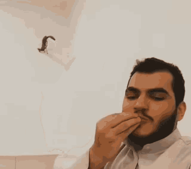 a man with a beard is eating something while a cat is flying in the air