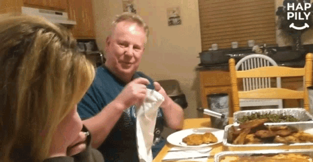a man and a woman are sitting at a table with plates of food and a sign that says hap pily on it