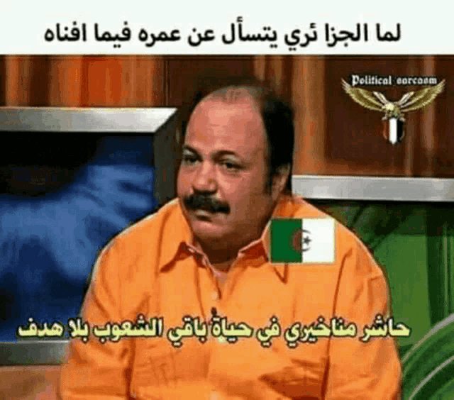 a man with a mustache is sitting in front of a television with a foreign language on it .