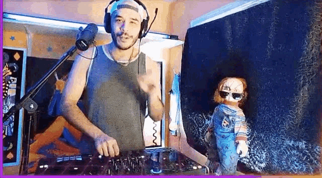 a man wearing headphones and a hat is playing a dj set with a doll behind him .