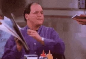 a man in a purple shirt is holding a piece of paper in his hand .
