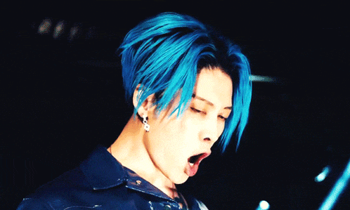 a close up of a person with blue hair and earrings