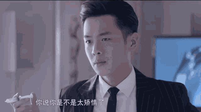 a man in a suit and tie is holding a pen with chinese writing on it