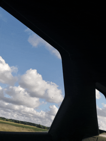 a car window shows a blue sky with clouds