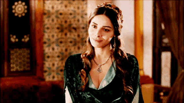 a woman in a green dress with a necklace on her neck