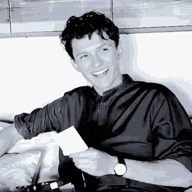 a black and white photo of a smiling man holding a piece of paper