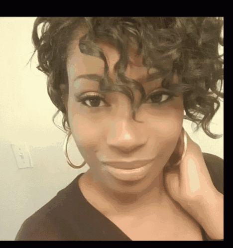 a close up of a woman 's face with curly hair and hoop earrings .