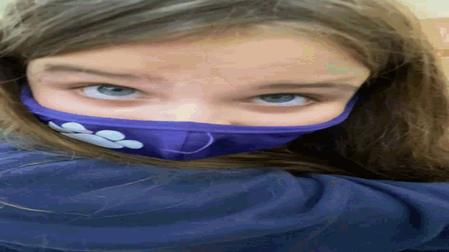 a young girl wearing a purple face mask with paw prints on it